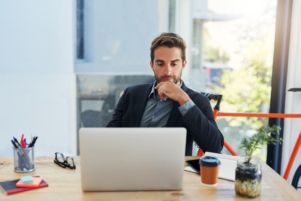 Business man thinking while on his laptop